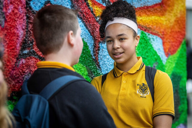 Pupils chatting next to a mural in the school yard